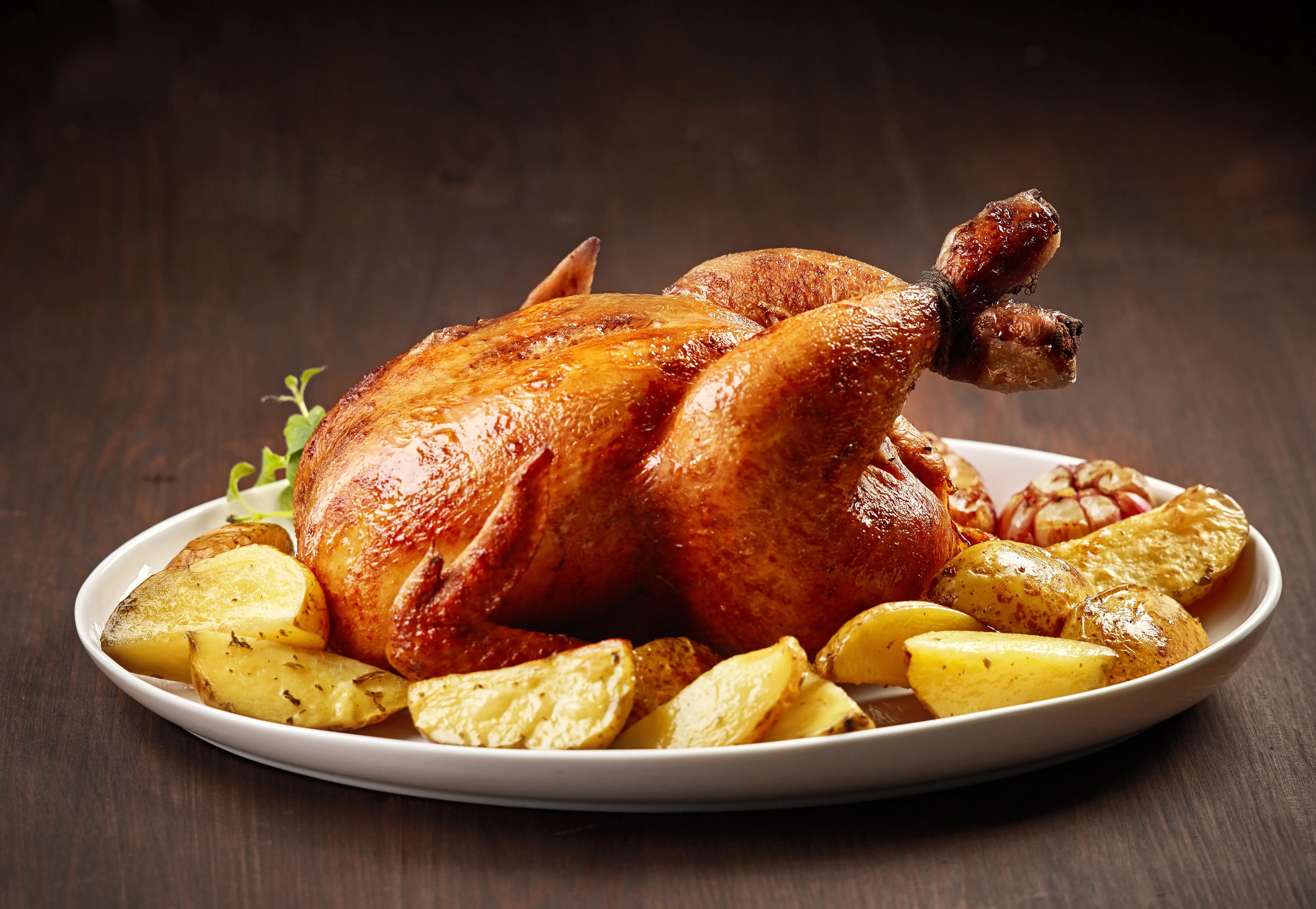 Pollo al horno con papas fritas en un plato blanco.